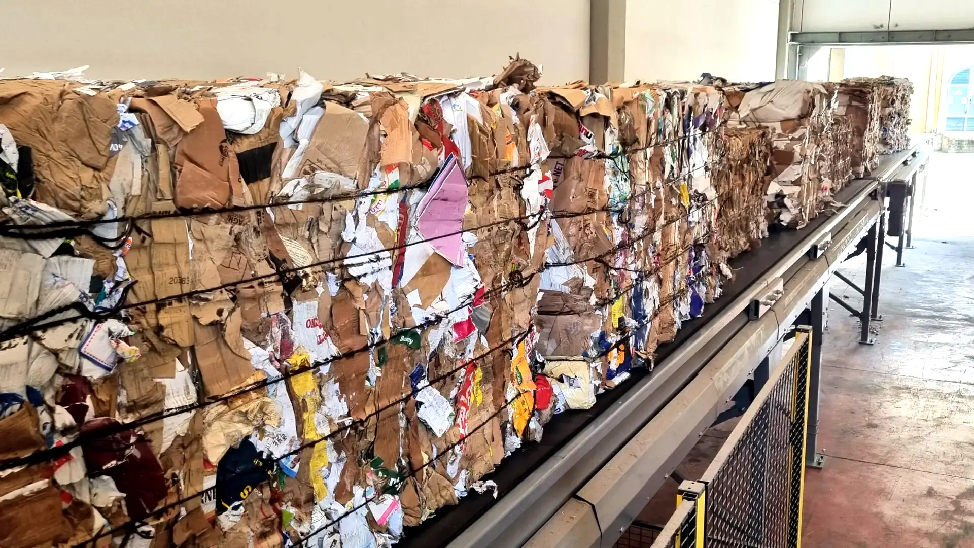 Recycled paper bales on a conveyor, ready for Bale Dewiring